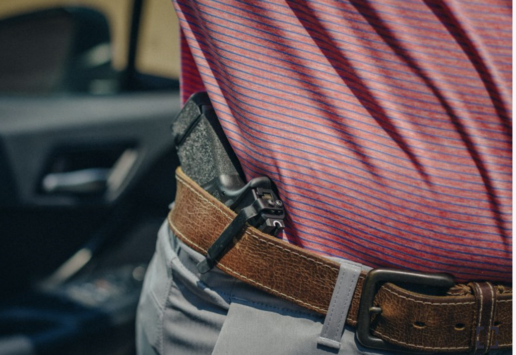 A person using a Clipdraw belt clip on their PSA Micro Dagger pistol to wear it in the side carry position inside their waistband.